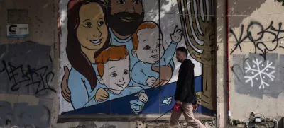 A man walks his dog past graffiti of Shiri and Yarden Bibas and their sons, Ariel, left, and Kfir, right, who were taken captive by Hamas, in Tel Aviv, Israel, Wednesday, Feb. 19, 2025. Yarden Bibas was freed from captivity earlier this month. (AP Photo/Oded Balilty)