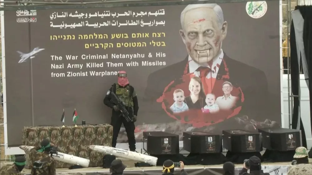 A Hamas militant stands near coffins during the handover of deceased hostages Oded Lifschitz, Shiri Bibas and her two children Kfir and Ariel Bibas, seized during the deadly October 7, 2023 attack, to the Red Cross, as part of a ceasefire and hostages-prisoners swap deal between Hamas and Israel, in Khan Younis in the southern Gaza Strip, in this still image taken from a video February 20, 2025. REUTERS/REUTERS TV