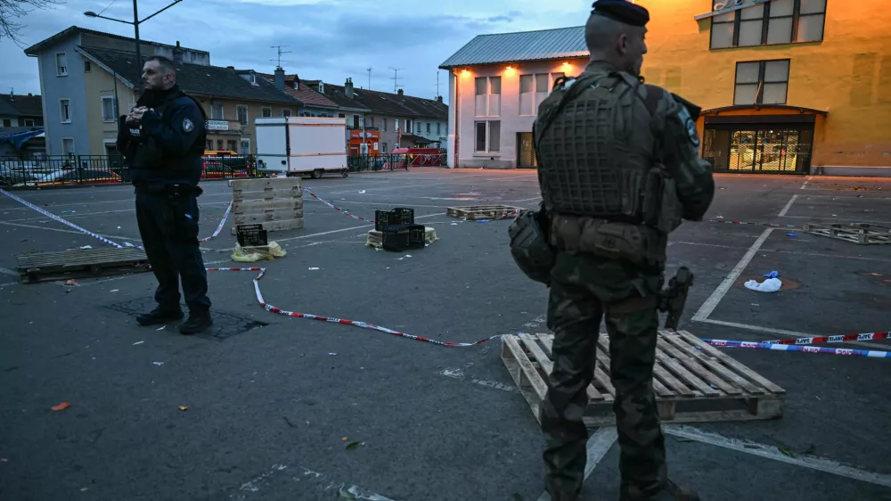 22 February 2025, France, Mulhouse: A police officer and a soldier stand at the site of a knife attack in Mulhouse. A man is suspected of killing one person and wounding two municipal police officers at a market in Mulhouse. Photo: Sebastien Bozon/AFP/dpa