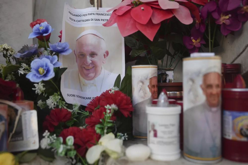 Candles and a photo of Pope Francis are seen in front of the Agostino Gemelli Polyclinic, in Rome, Saturday, Feb. 22, 2025, where the Pontiff is hospitalized since Friday, Feb. 14.(AP Photo/Alessandra Tarantino)