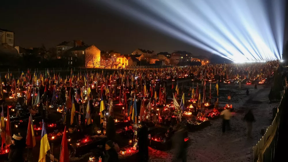 People visit the graves of their relatives, who were killed during Russia's attack on Ukraine, during a large-scale light installation "Lights of Memory" as they mark the third anniversary of the full-scale Russian invasion, at the Lychakiv cemetery in Lviv, Ukraine February 23, 2025. REUTERS/Roman Baluk