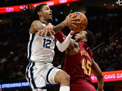 Feb 23, 2025; Cleveland, Ohio, USA; Memphis Grizzlies guard Ja Morant (12) is fouled by Cleveland Cavaliers guard Donovan Mitchell (45) during the second half at Rocket Arena. Mandatory Credit: Ken Blaze-Imagn Images