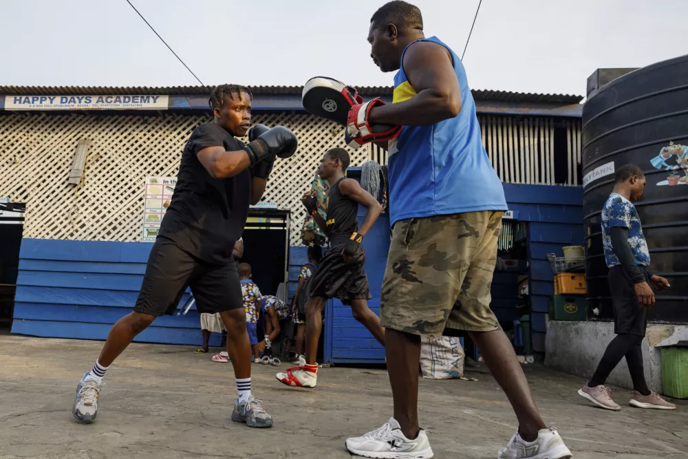 Ebenezer Adjei, right, Abigail Kwartekaa Quartey's coach, helps her in an evening training session at a school compound in the Jamestown district in Accra, Ghana, Wednesday, Jan. 22, 2025. (AP Photo/Misper Apawu)