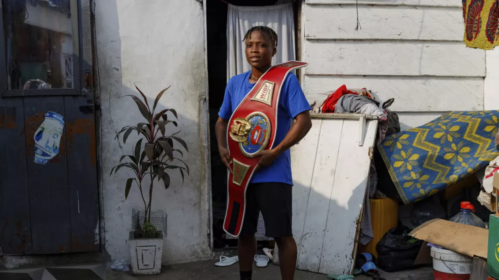 Ghana's first-ever female world boxing champion, Abigail Kwartekaa Quartey, poses for a photo with her world title belt at her house in the Jamestown district in Accra, Ghana, Wednesday, Jan. 22, 2025. (AP Photo/Misper Apawu)