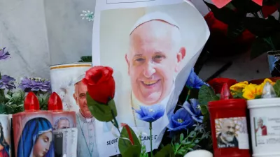 A photo of Pope Francis is placed next to candles and flowers at the base of the statue of the late Pope John Paul II outside the Gemelli Hospital where Pope Francis is admitted for treatment, in Rome, Italy, February 23, 2025. REUTERS/Ciro De Luca