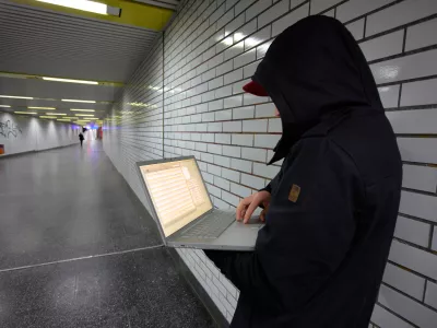 C8JB5H Computer user, hacker, sits conspiratorially with a laptop, in a subway station. Symbol picture, computer-Internet crime.