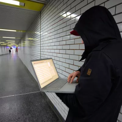 C8JB5H Computer user, hacker, sits conspiratorially with a laptop, in a subway station. Symbol picture, computer-Internet crime.