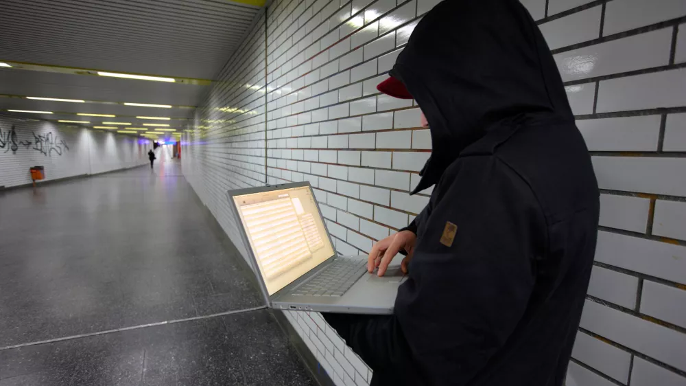 C8JB5H Computer user, hacker, sits conspiratorially with a laptop, in a subway station. Symbol picture, computer-Internet crime.