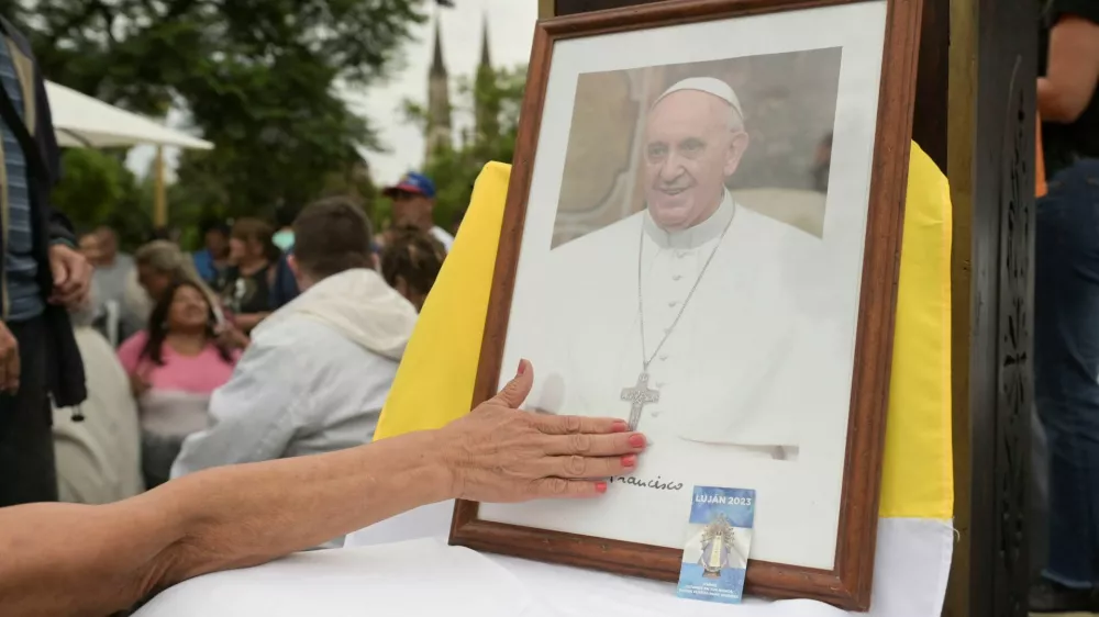 A person touches a portrait of Pope Francis during a Mass to pray for Pope Francis' health at the Plaza Constitucion in Buenos Aires, Argentina, February 24, 2025. REUTERS/Martin Cossarini