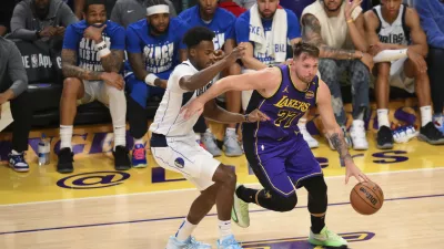 Los Angeles Lakers guard Luka Doncic (77) moves the ball past Dallas Mavericks forward Olivier-Maxence Prosper during the second half of an NBA basketball game Tuesday, Feb. 25, 2025, in Los Angeles. (AP Photo/Kyusung Gong)