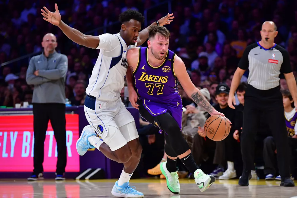 Feb 25, 2025; Los Angeles, California, USA; Los Angeles Lakers guard Luka Doncic (77) dribbles the ball past Dallas Mavericks forward Olivier-Maxence Prosper (8) during the second half at Crypto.com Arena. Mandatory Credit: Gary A. Vasquez-Imagn Images