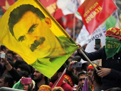 FILE - In this file photo dated Wednesday, March 21, 2018, a youth holds a flag with the image of Abdullah Ocalan, the jailed leader of the rebel Kurdistan Workers' Party, or PKK, in Istanbul, Turkey. (AP Photo/Lefteris Pitarakis, File)