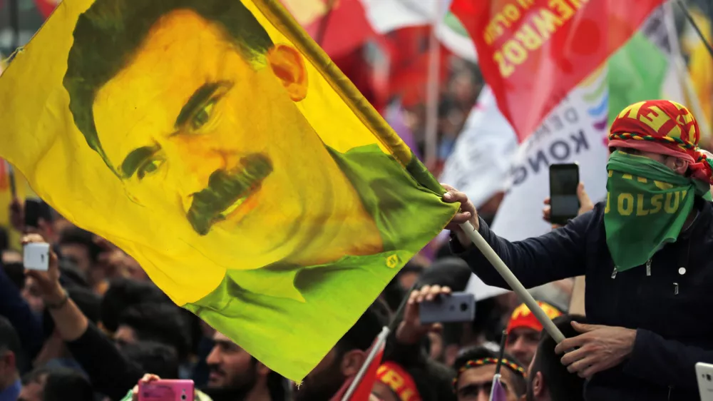 FILE - In this file photo dated Wednesday, March 21, 2018, a youth holds a flag with the image of Abdullah Ocalan, the jailed leader of the rebel Kurdistan Workers' Party, or PKK, in Istanbul, Turkey. (AP Photo/Lefteris Pitarakis, File)