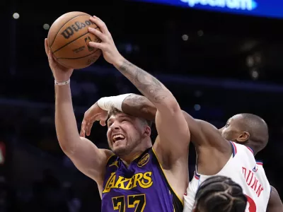 Los Angeles Lakers guard Luka Doncic, left, shoots as Los Angeles Clippers guard Kris Dunn defends during the second half of an NBA basketball game, Friday, Feb. 28, 2025, in Los Angeles. (AP Photo/Mark J. Terrill)