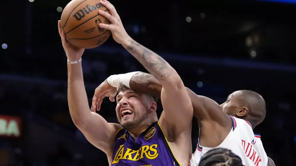 Los Angeles Lakers guard Luka Doncic, left, shoots as Los Angeles Clippers guard Kris Dunn defends during the second half of an NBA basketball game, Friday, Feb. 28, 2025, in Los Angeles. (AP Photo/Mark J. Terrill)