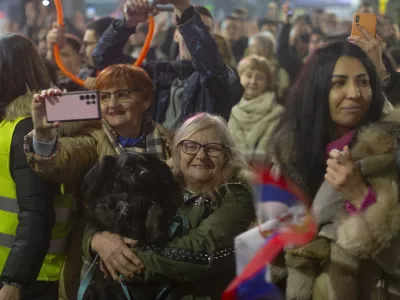 A person carries a dog as she and others await the arrival of university students to the town of Nis, Serbia, to protest the deaths of 15 people killed in the November 2024 collapse of a train station canopy, Friday, Feb. 28, 2025. (AP Photo/Marko Drobnjakovic)