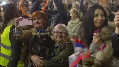 A person carries a dog as she and others await the arrival of university students to the town of Nis, Serbia, to protest the deaths of 15 people killed in the November 2024 collapse of a train station canopy, Friday, Feb. 28, 2025. (AP Photo/Marko Drobnjakovic)