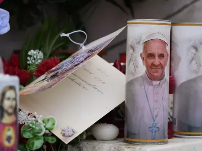 Candles with the pictures of Pope Francis are the laid under the statue of late Pope John Paul II outside Agostino Gemelli Polyclinic in Rome, Wednesday, Feb. 19, 2025, where the Pontiff is hospitalized since Friday, Feb. 14. (AP Photo/Gregorio Borgia)