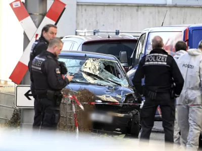 Police officers stand next to a damaged vehicle in the city center of Mannheim, Germany, Monday March 3, 2025, following an incident in which one person was killed and others injured when a car rammed into a crowd, German police said. (Boris Roessler/dpa via AP)