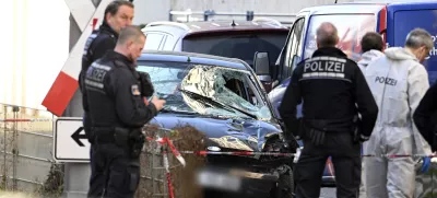 Police officers stand next to a damaged vehicle in the city center of Mannheim, Germany, Monday March 3, 2025, following an incident in which one person was killed and others injured when a car rammed into a crowd, German police said. (Boris Roessler/dpa via AP)