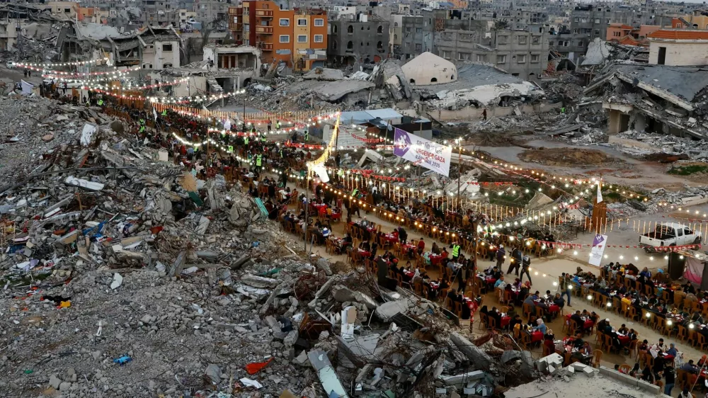 FILE PHOTO: Palestinians break their fast by eating the Iftar meals during the holy month of Ramadan, near the rubble of buildings, amid a ceasefire between Israel and Hamas, in Rafah, in the southern Gaza Strip, March 1, 2025. REUTERS/Hatem Khaled/File Photo