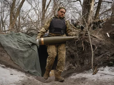 An Ukrainian serviceman carries a shell to fire a M777 howitzer towards Russian positions at the frontline near Donetsk, Ukraine, Sunday, March, 2, 2025. (AP Photo/Roman Chop)