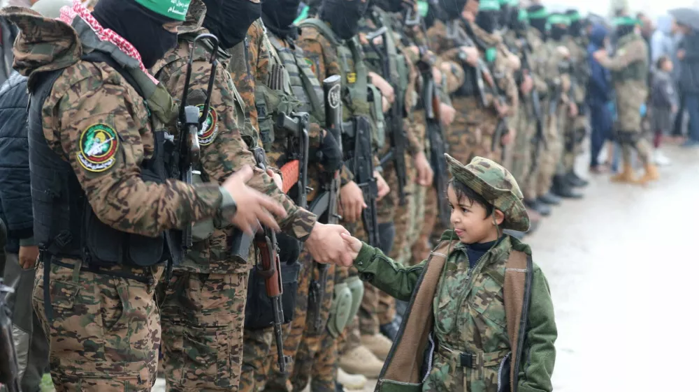 FILE PHOTO: A Palestinian Hamas militant shakes hands with a child as they stand guard as people gather on the day of the handover of hostages, including four held in Gaza since the deadly October 7 2023 attack, to members of the International Committee of the Red Cross (ICRC) as part of a ceasefire and a hostages-prisoners swap deal between Hamas and Israel, in Rafah in the southern Gaza Strip, February 22, 2025. REUTERS/Ramadan Abed/File Photo