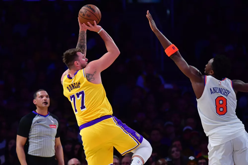 Mar 6, 2025; Los Angeles, California, USA; Los Angeles Lakers guard Luka Doncic (77) shoots against New York Knicks forward OG Anunoby (8) during the first half at Crypto.com Arena. Mandatory Credit: Gary A. Vasquez-Imagn Images