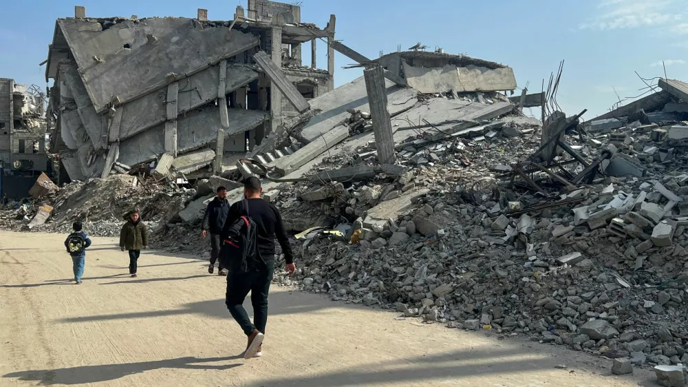 Palestinians walk past the rubble of destroyed houses, amid a ceasefire between Israel and Hamas, in Khan Younis in the southern Gaza Strip, March 6, 2025. REUTERS/Hussam Al-Masri