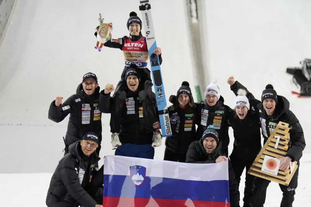 Nika Prevc, of Slovenia, poses with her team after winning the gold medal in the ski jumping women's large hill individual competition at the Nordic World Ski Championships in Trondheim, Norway, Friday, March 7, 2025. (AP Photo/Matthias Schrader)