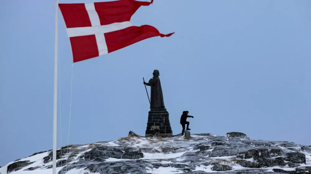 FILE PHOTO: A man walks as Danish flag flutters next to Hans Egede Statue ahead of a March 11 general election in Nuuk, Greenland, March 9, 2025. REUTERS/Marko Djurica/File Photo