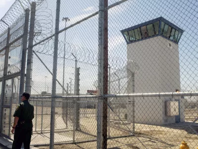 FILE - A correctional officer walks near a gate, which is one of two entrances into Kern Valley State Prison, June 14, 2005, in Delano, Calif. (AP Photo/Ric Francis,File)