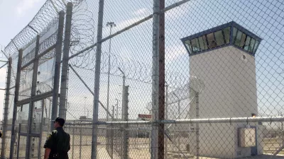 FILE - A correctional officer walks near a gate, which is one of two entrances into Kern Valley State Prison, June 14, 2005, in Delano, Calif. (AP Photo/Ric Francis,File)