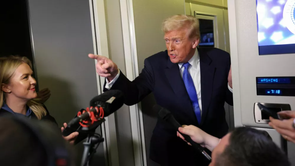 U.S. President Donald Trump speaks to reporters as White House Press Secretary Karoline Leavitt stands with him aboard Air Force One on his return to Washington, D.C., U.S., March 9, 2025. REUTERS/Kevin Lamarque