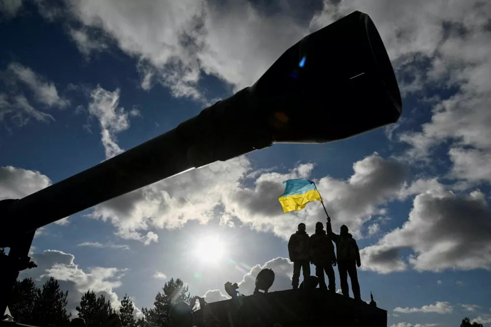 FILE PHOTO: Ukrainian personnel hold a Ukrainian flag as they stand on a Challenger 2 tank during training at Bovington Camp, near Wool in southwestern Britain, February 22, 2023. REUTERS/Toby Melville/File Photo