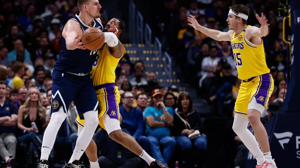 Mar 14, 2025; Denver, Colorado, USA; Denver Nuggets center Nikola Jokic (15) passes the ball under pressure from Los Angeles Lakers forward Markieff Morris (88) as guard Austin Reaves (15) defends in the third quarter at Ball Arena. Mandatory Credit: Isaiah J. Downing-Imagn Images