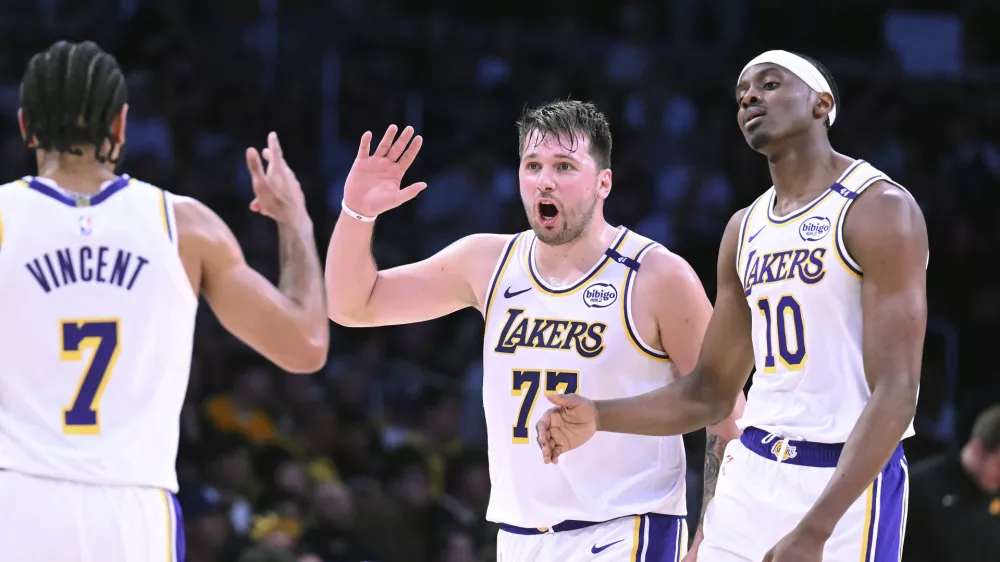 Los Angeles Lakers guard Luka Doncic (77) celebrates with guard Gabe Vincent (7) and center Christian Koloko (10) after a three-point basket against the Phoenix Suns during the first half of an NBA basketball game Sunday, March 16, 2025, in Los Angeles. (AP Photo/Wally Skalij)