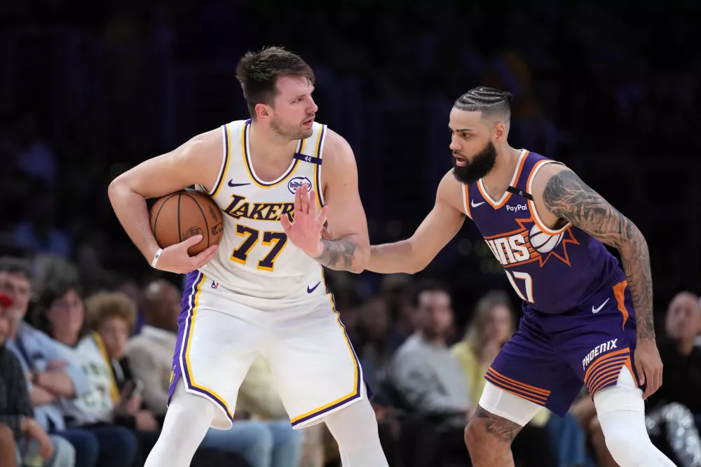 Mar 16, 2025; Los Angeles, California, USA; Los Angeles Lakers guard Luka Doncic (77) is defended by Phoenix Suns forward Cody Martin (17) in the second half at Crypto.com Arena. Mandatory Credit: Kirby Lee-Imagn Images