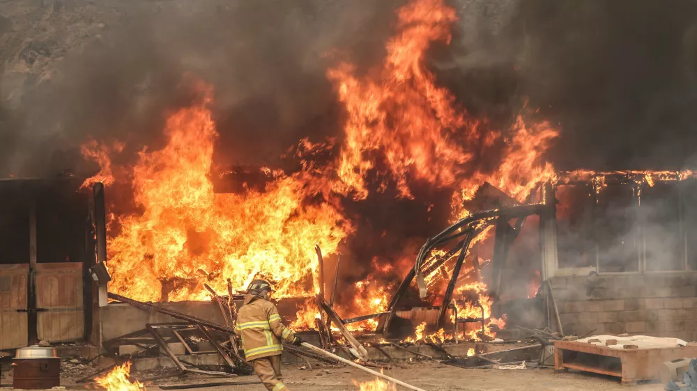 A firefighter works to extinguish a fire at a house that has been engulfed in a wildfire in Uiseong, South Korea, Tuesday, March 25, 2025. (Yoon Gwan-shick/Yonhap via AP)