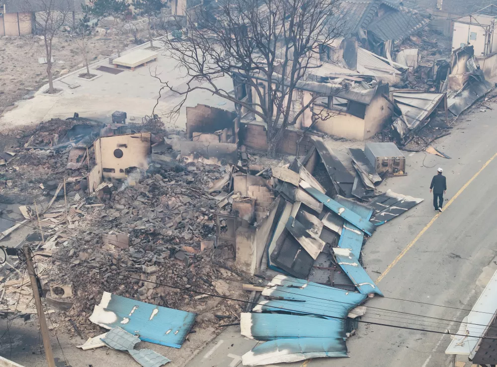 A man walks near a burnt-out house in a damaged village in Yeongyang, South Korea, Wednesday, March 26, 2025. (Yun Kwan-shik/Yonhap via AP)