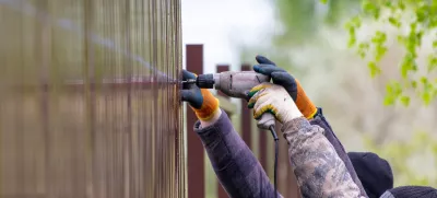 Workers install a metal profile fence. / Foto: Schankz