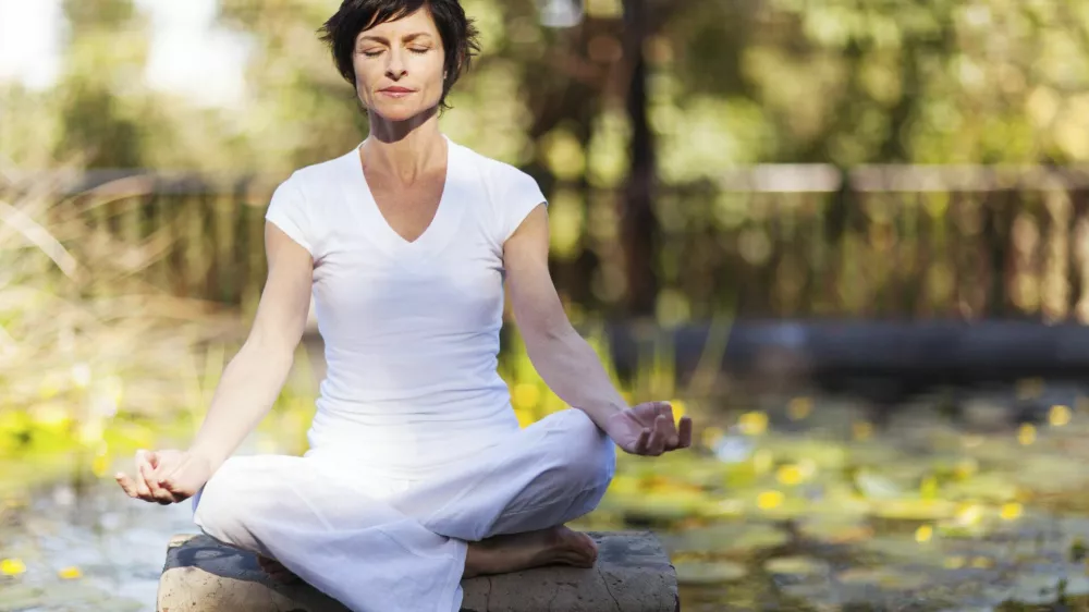 middle aged woman doing yoga meditation