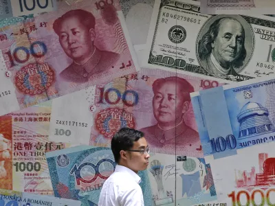 ﻿FILE - In this June 10, 2019, file photo, a man walks past a money exchange shop decorated with different banknotes at Central, a business district of Hong Kong. China's yuan fell Friday, Aug. 2, 2019, to its lowest level of the year against the dollar following U.S. President Donald Trump's threat of new tariffs on Chinese goods, coming close to breaking the politically sensitive level of seven to the U.S. currency. (AP Photo/Kin Cheung, File)