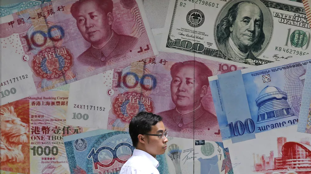 ﻿FILE - In this June 10, 2019, file photo, a man walks past a money exchange shop decorated with different banknotes at Central, a business district of Hong Kong. China's yuan fell Friday, Aug. 2, 2019, to its lowest level of the year against the dollar following U.S. President Donald Trump's threat of new tariffs on Chinese goods, coming close to breaking the politically sensitive level of seven to the U.S. currency. (AP Photo/Kin Cheung, File)