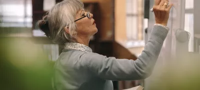 Side view of a senior female teacher writing on a white board in classroom. Close up of a woman lecturer teaching in classroom. / Foto: Jacoblund