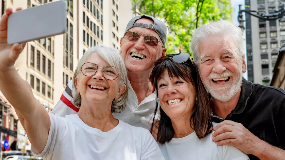 A cheerful group of senior retired friends visiting New York City take a selfie on the street. Two couples of travelers on a leisure vacation enjoy the journey and freedom / Foto: Lucigerma