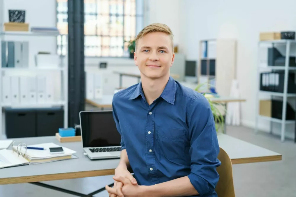 Friendly relaxed young businessman in the office turning in his chair to look at the camera with a warm smile / Foto: Stockfour