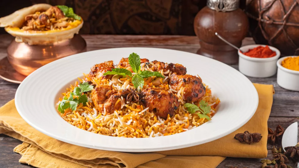 A closeup of chicken biryani dish served on a wooden table / Foto: Wirestock