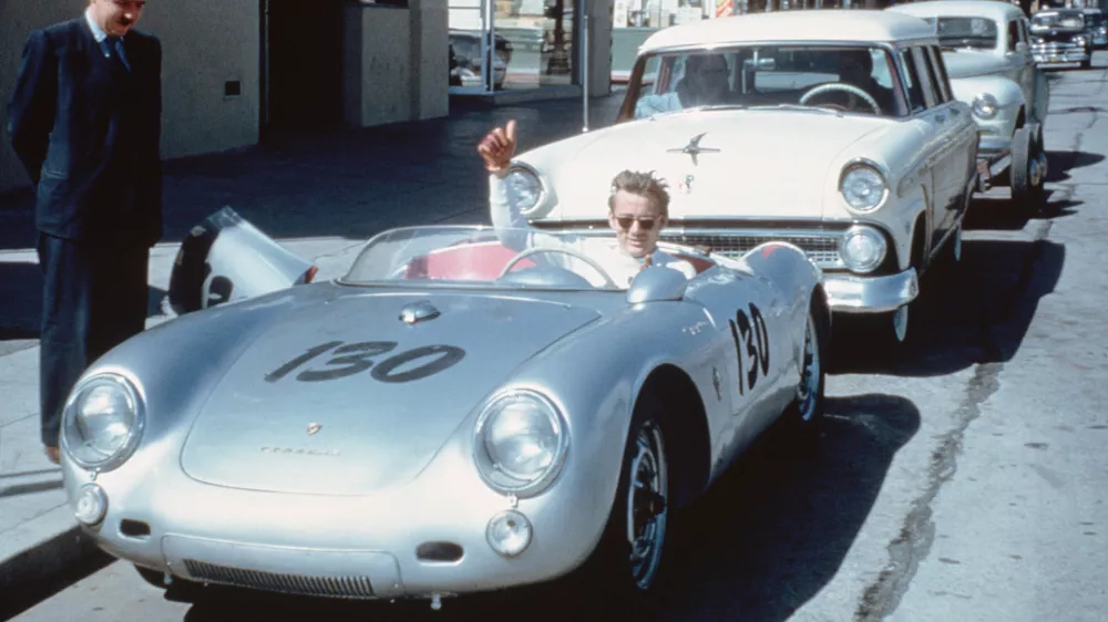 James Dean waves from behind the wheel of his Porsche 550 Spyder 'Little Bastard' numbered 130 (VIN 550-0055) parked on Vine Street in Los Angeles, California, USA. (Photo by Bettmann via Getty Images) / Foto: Bettmann