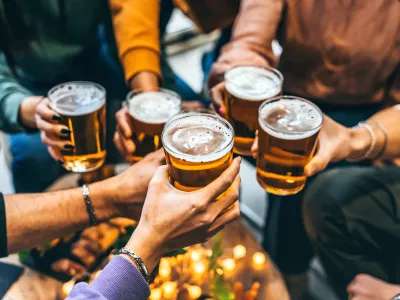 Group of friends drinking and toasting glass of beer at brewery pub restaurant- Happy multiracial people enjoying happy hour with pint sitting at bar table- Youth Food and beverage lifestyle concept / Foto: Nicolas Micolani